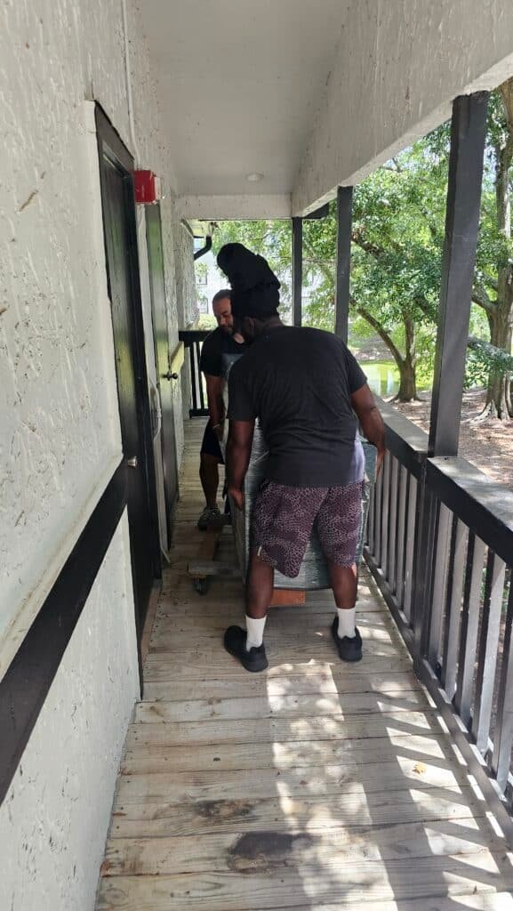 Home 13 Safe moving services. Two men bringing a safe into an apartment.