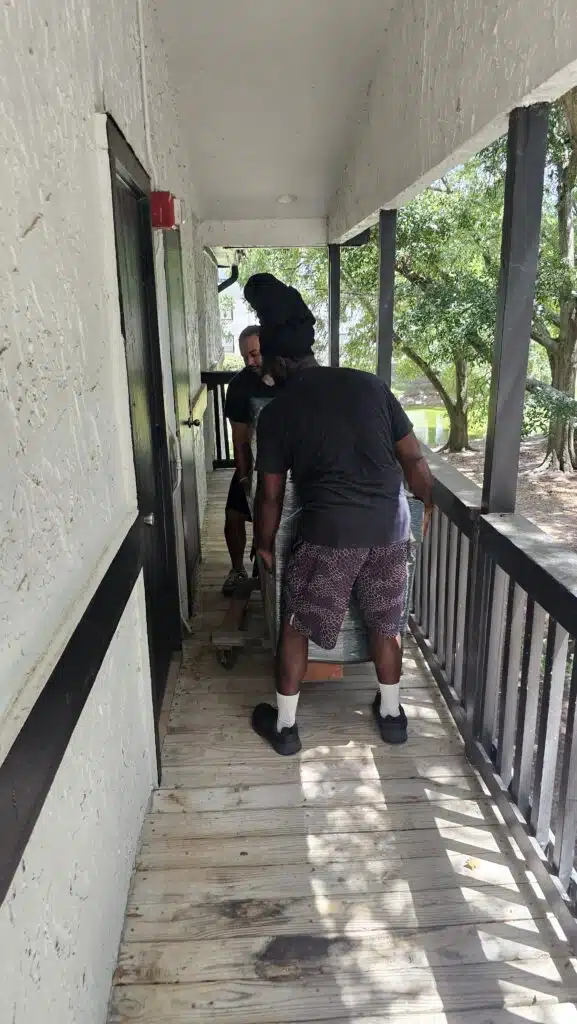 Services 32 Safe moving services. Two men bringing a safe into an apartment.