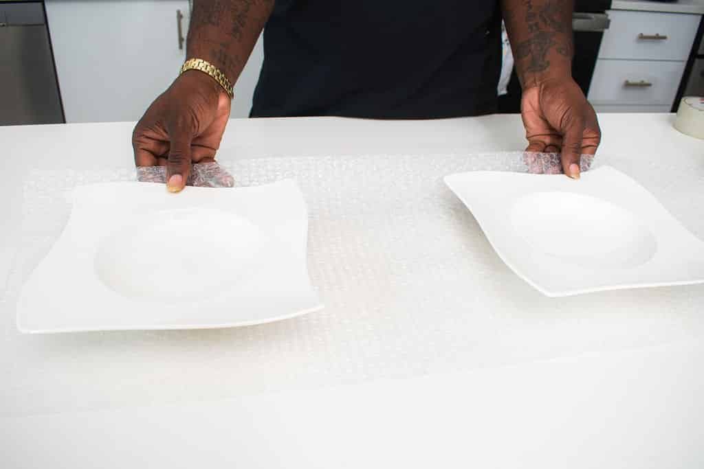 Person holding plates over bubble wrap. moving company in Palm Valley