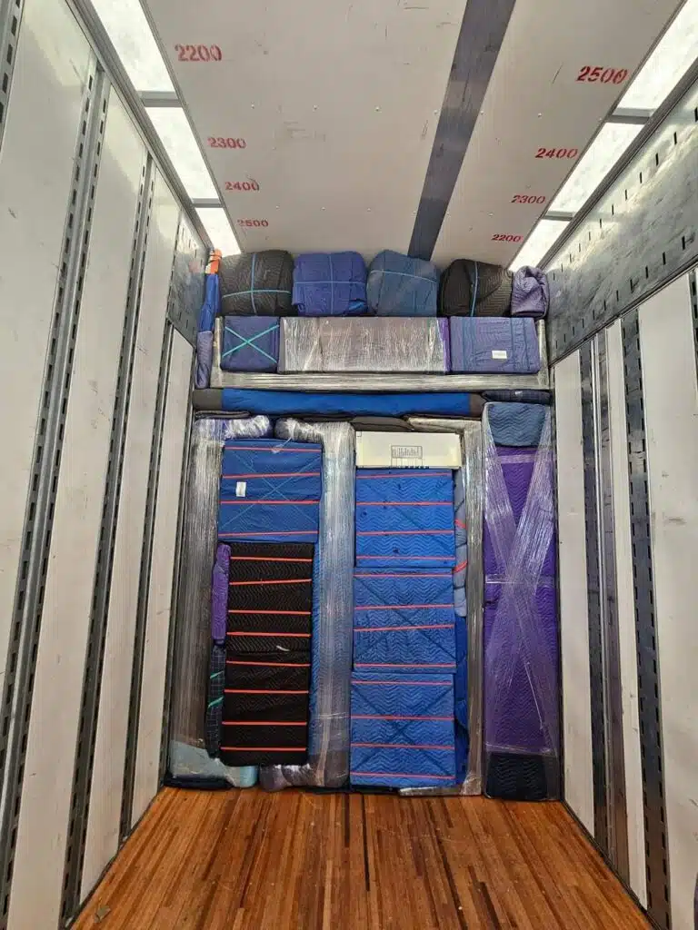 Moving truck container packed with secured and padded items.
